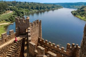 A woman in pink sitting on the steps of Almourol Castle in Central Portugal